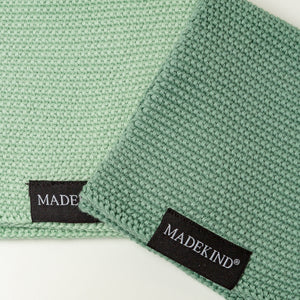 Photo of two green madekind cloths with the logos on the front